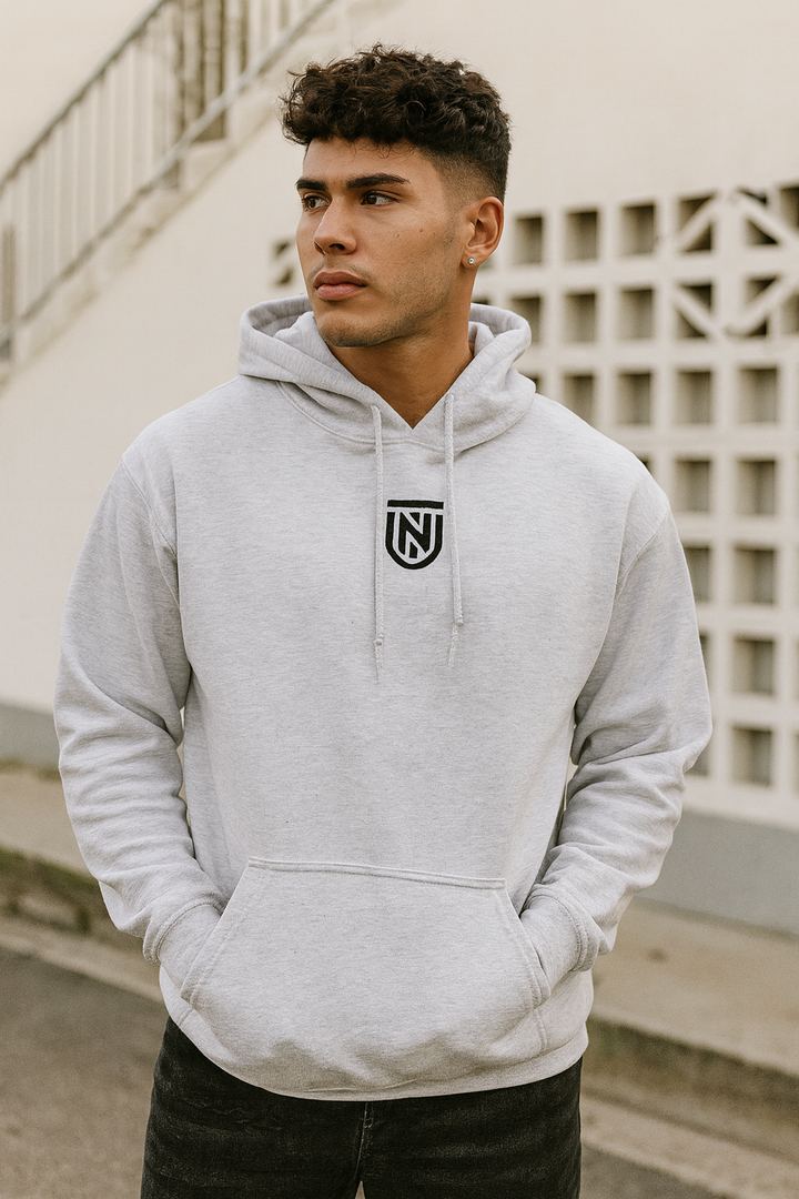 Man wearing a gray hoodie with a logo, standing outdoors.