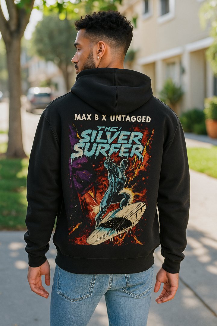 Person wearing a black hoodie with 'The Silver Surfer' graphic design outdoors.