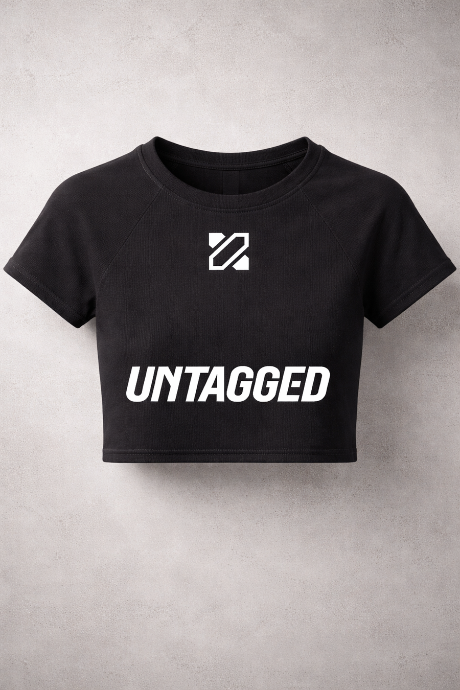 Black crop top with 'UNTAGGED' text and logo on a gray background