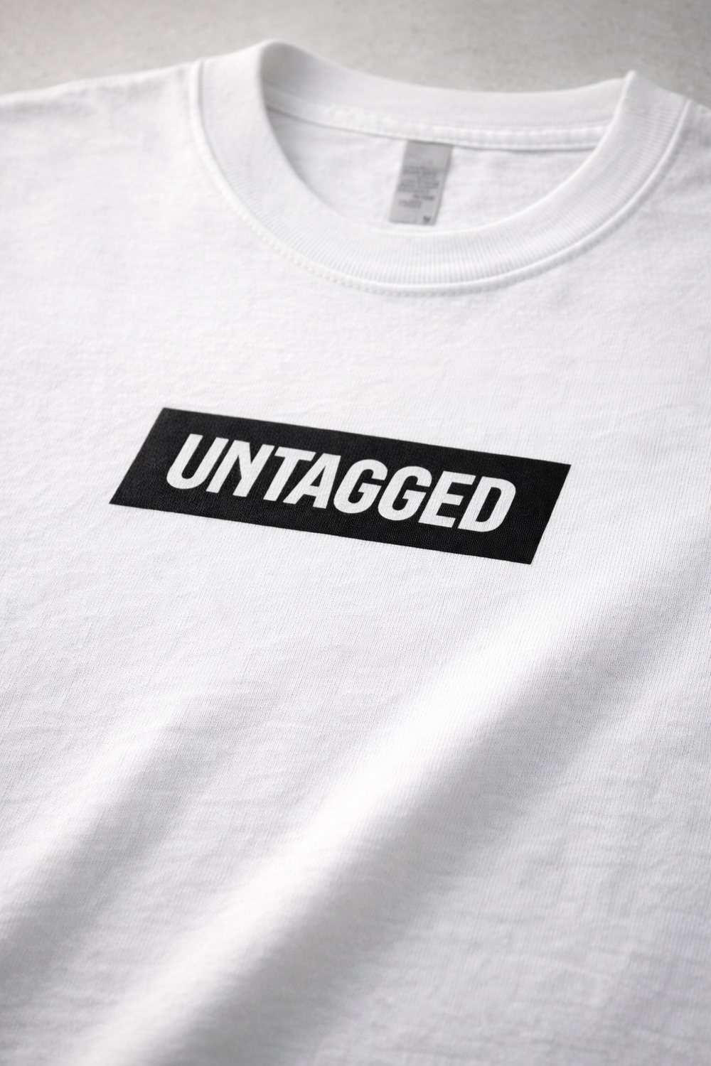 White t-shirt with 'UNTAGGED' label on a gray background