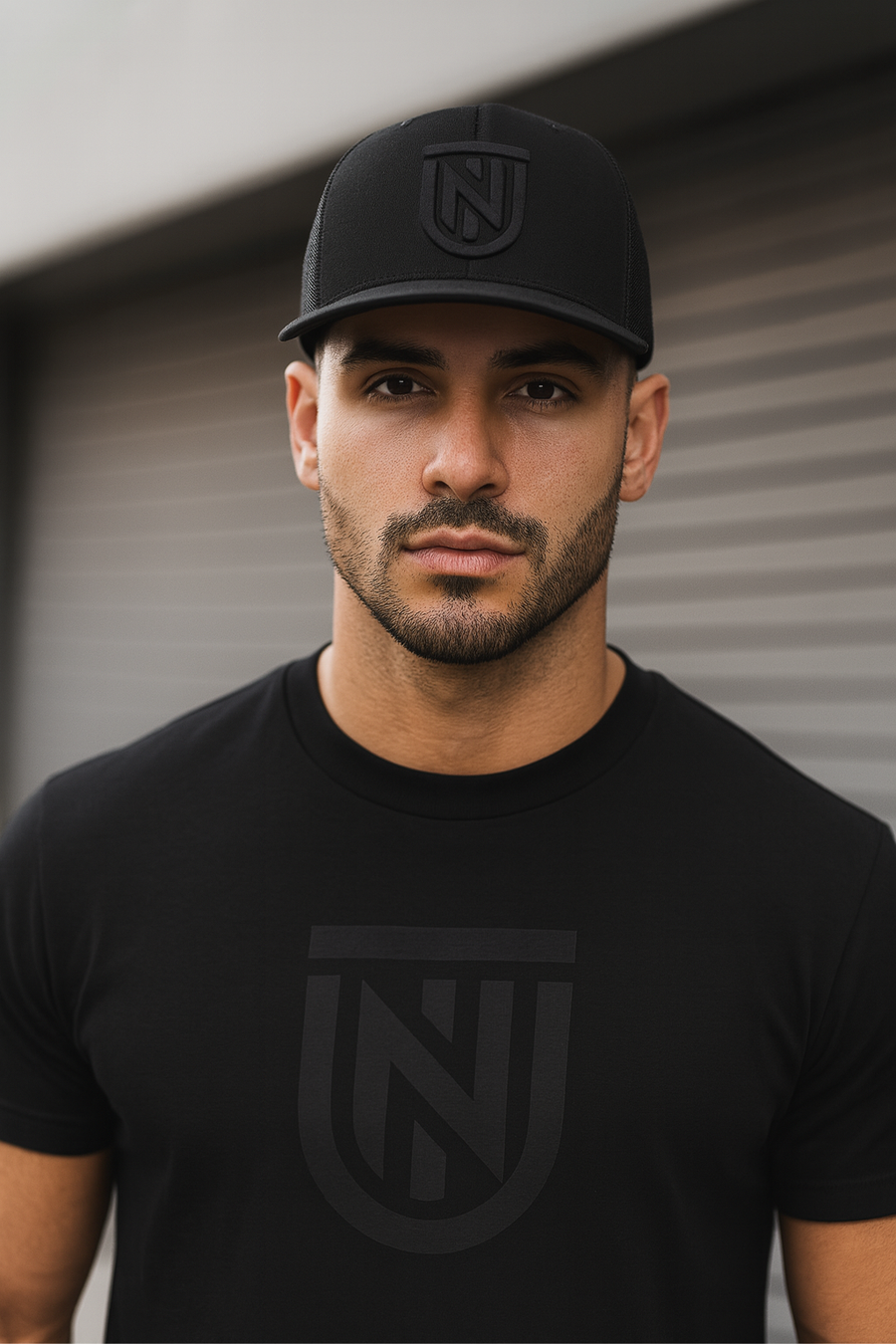Man wearing a black cap and t-shirt with a logo against a neutral background