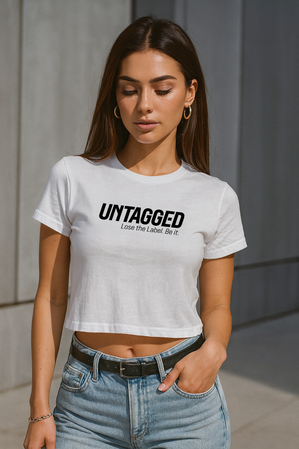 Woman wearing a white t-shirt with 'UNTAGGED' text, standing against a neutral background.